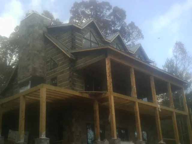 Stone chimney and dormers on a large log home with a timber porch in Montpelier